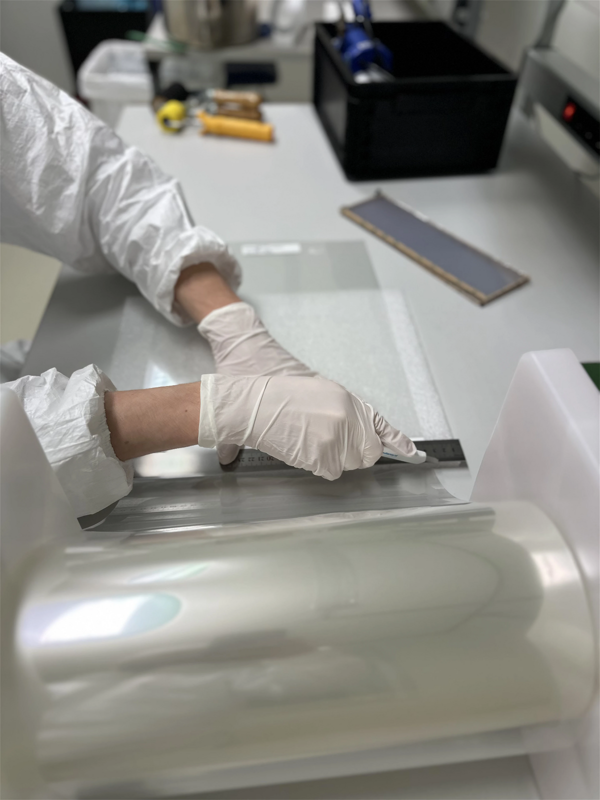 Gloved hands cutting protective film in a clean room