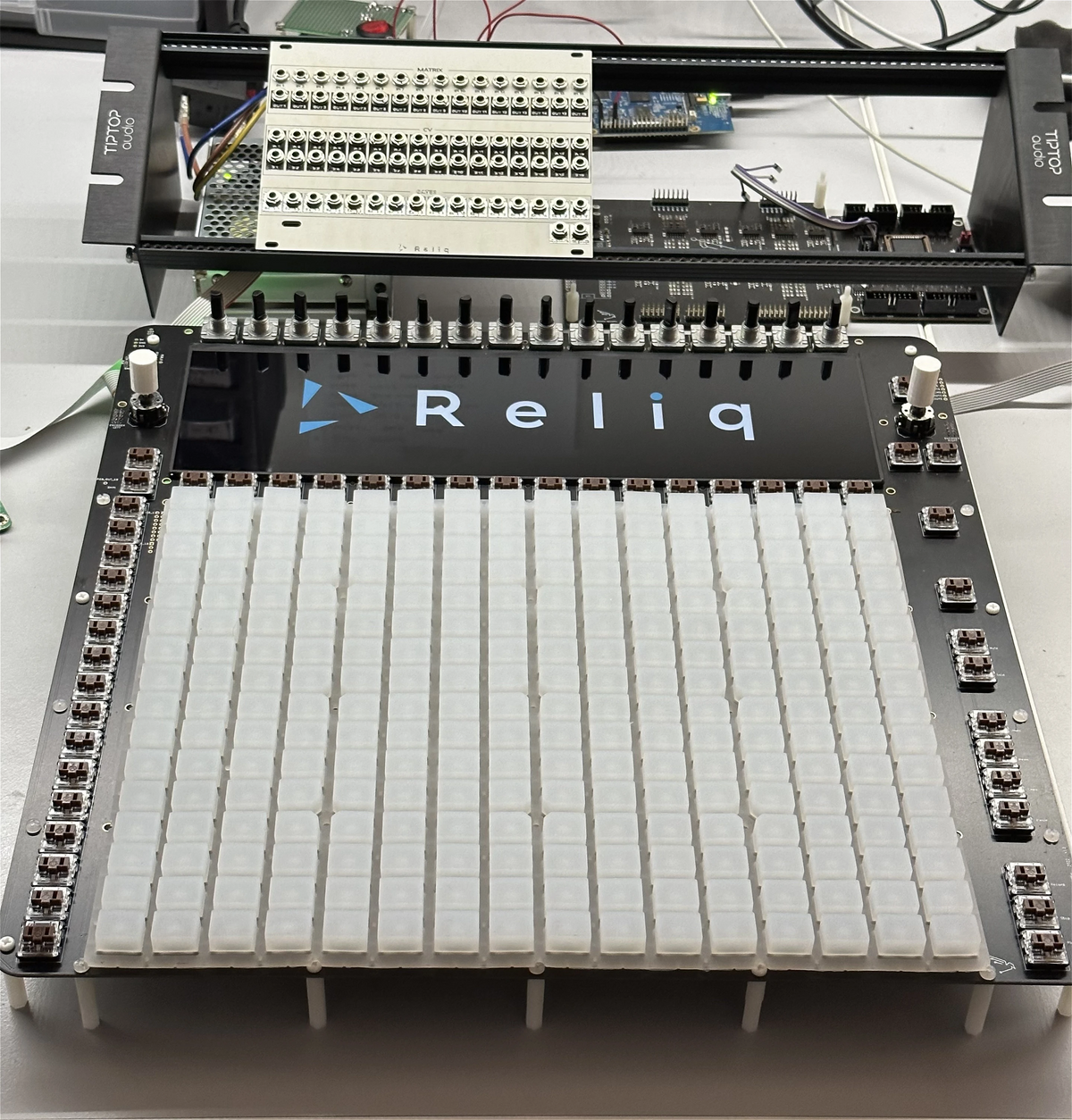 Prototype with sixteen encoders above the screen and the pad grid below, connectors moved to a separate module