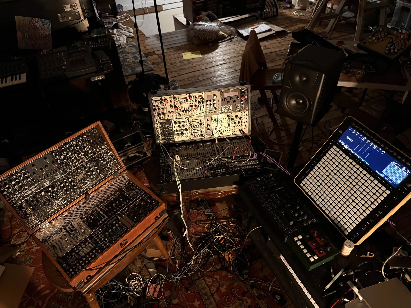 Modular cases, synths and Reliq on a stand in a dim studio